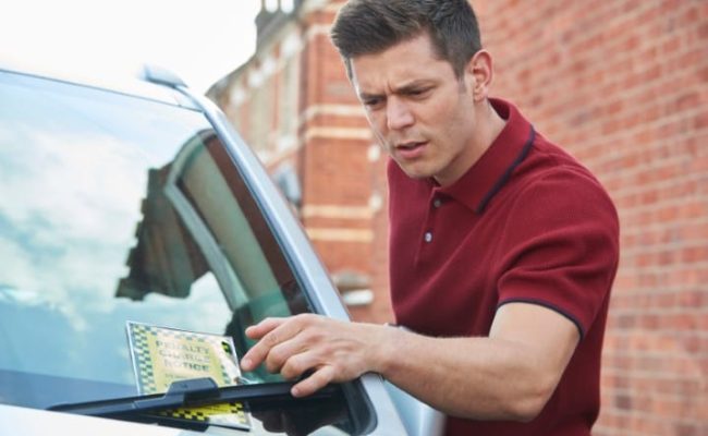 Frustrated Male Motorist Looking At Parking Ticket
